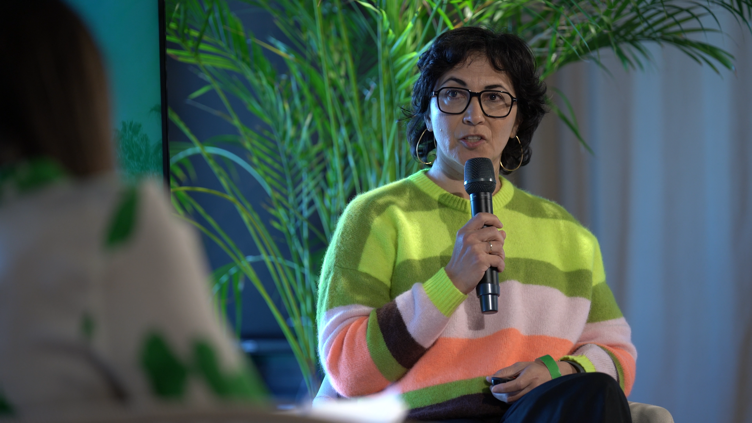Speaker in a striped sweater holding a microphone